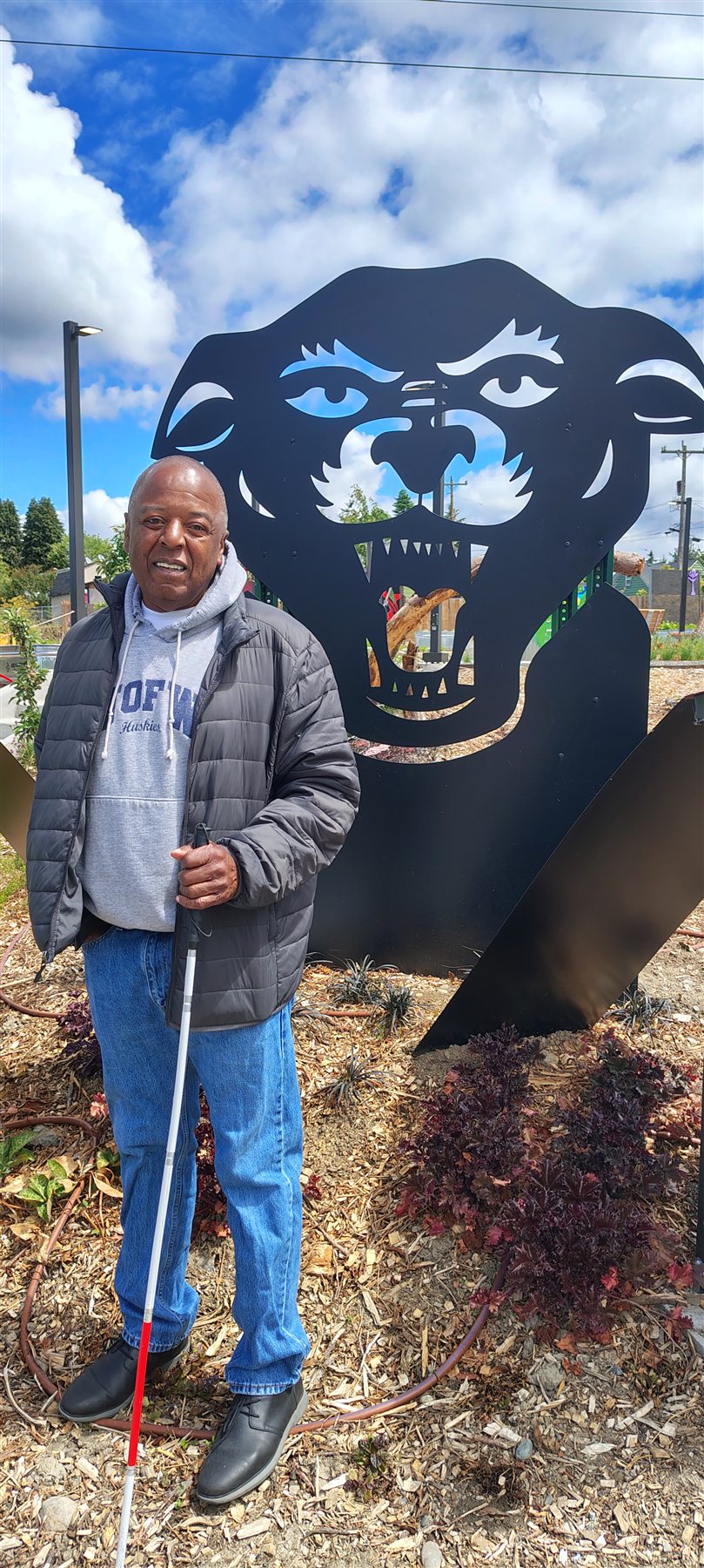 John Houston standing beside the black panther sculpture at Black Panther Park.